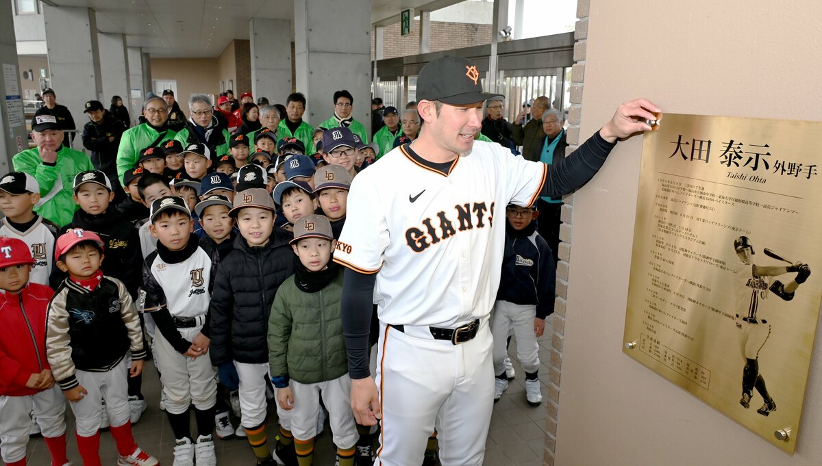 祝福を受け、壁面に掲げられた記念プレートのボルトを締める大田さん(手前)