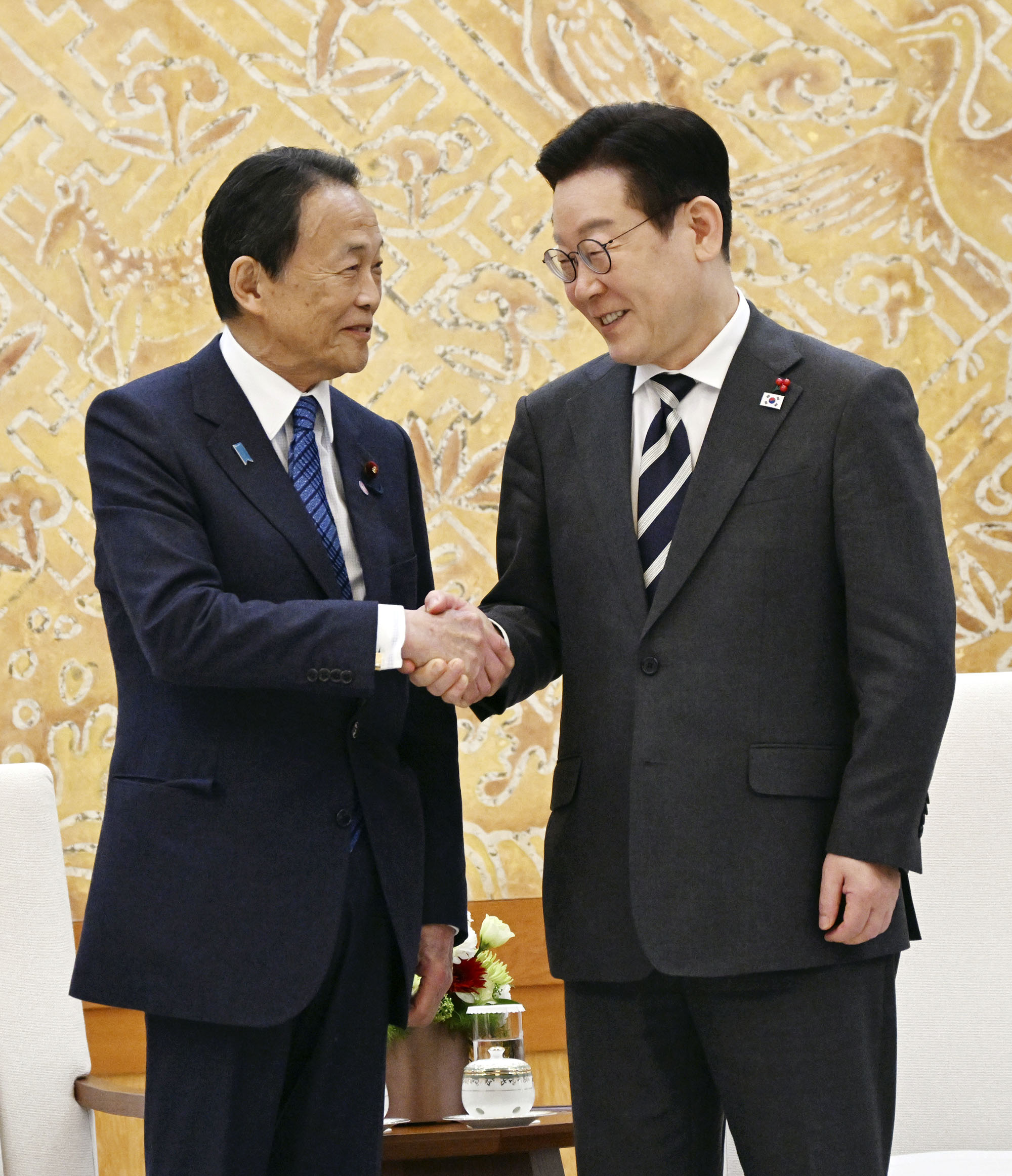 韓国の李在明大統領(右)と握手を交わす自民党の麻生副総裁=16日、韓国大統領府(共同)