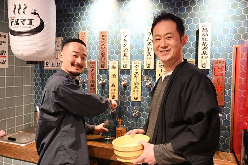 「水道の蛇口からお酒を注ぐ非日常感を楽しんで」と話す高橋光基社長(左)とFC店オーナーの渡辺靖之代表=川越市の大衆酒泉テルマエ本川越駅クレアモール泉