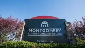 Montgomery County Community College sign surrounded by plants on a sunny day.