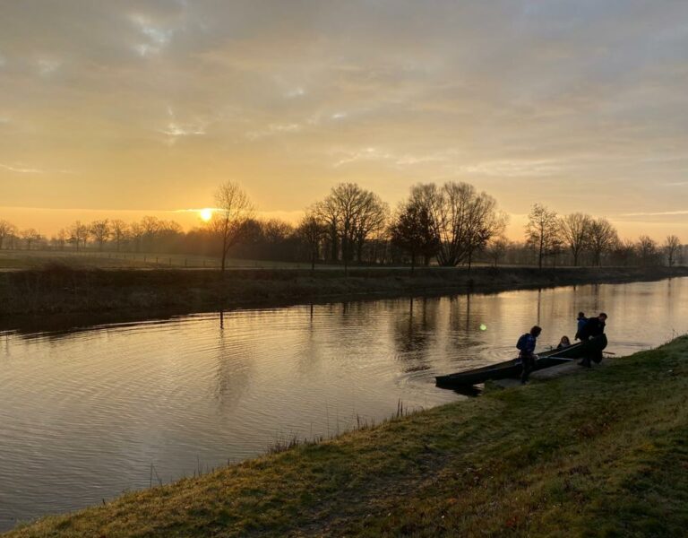 Zonsopgang boven een rivier met FNL leden die zich voorbereiden op een kano activiteit