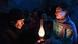 A man looks at a lantern a woman is holding with her hands. A man looks at a lantern a woman is holding with her hands.