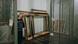 A man walking in a hall where empty artwork frames are piled against the wall. A man walking in a hall where empty artwork frames are piled against the wall.