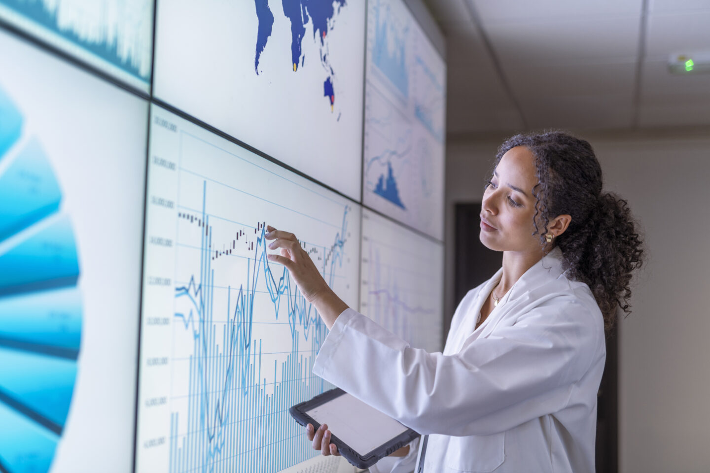 Image of female researcher inspecting charts on interactive screens.