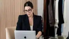 Amanda Wood upper body headshot as she types on Apple laptop with clothing rack in background.