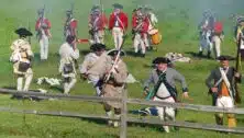 Revolutionary War reenactment on field with soldiers from both sides.