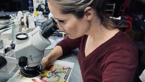 Emily Meyers looks at a comic book under a microscope.
