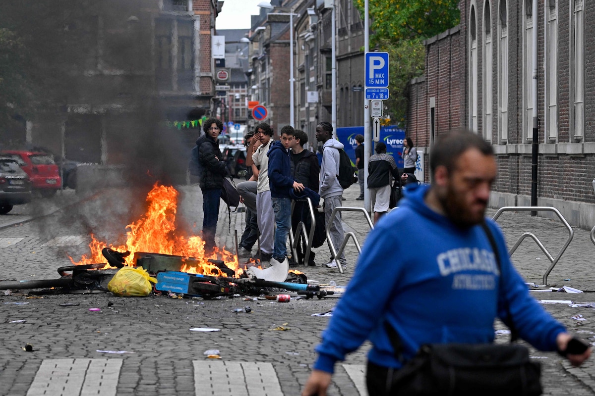 A pedestrian walk past a fire during a spontaneous protest of high school students against education reforms by the Wallonia-Brussels Federation government and a rise in student fees in Liege on October 1, 2026. (Photo by JOHN THYS / AFP)