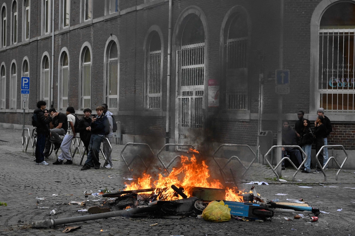 This photograph shows a fire as high school students take part in a spontaneous protest against education reforms by the Wallonia-Brussels Federation government and a rise in student fees in Liege on October 1, 2026. (Photo by JOHN THYS / AFP)