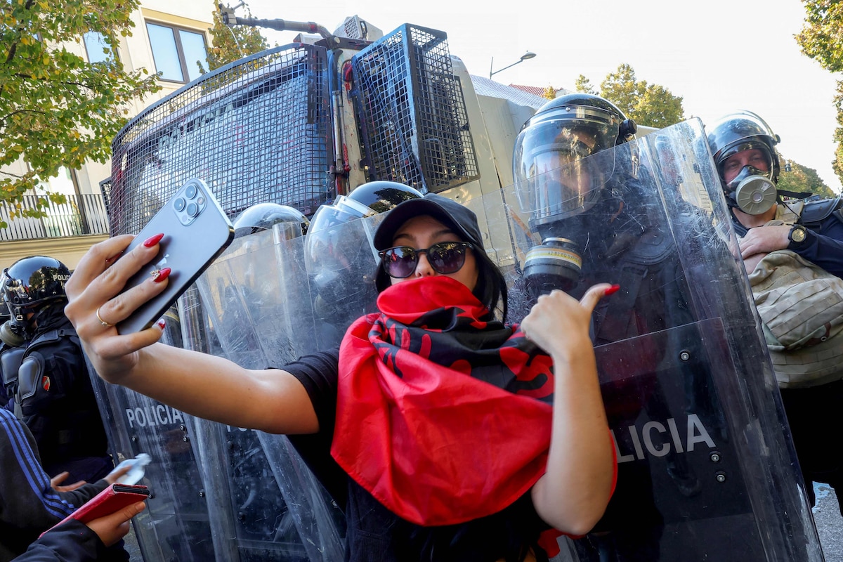 A protester takes a selfie with riot police officers during an anti-government demonstration in central Tirana on October 20, 2026, after a week of violent anti-government protests. Albanian Prime Minister on October 20, 2026 blamed a "hybrid war" for fuelling unrest in his country, after a week of violent anti-government demonstrations in Tirana. Demonstrators have repeatedly clashed with police as months of protests escalate, driven by fresh demands for better university conditions, anger over corruption and renewed calls for Prime Minister's resignation. (Photo by Adnan Beci / AFP)
