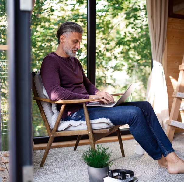 A person sitting in a chair while working on a laptop.