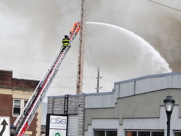 A firefighter on an aerial hose ladder direct water on...
