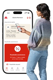 Standing next to an enlarged image of the State Farm app, a young lady checks her smartphone.