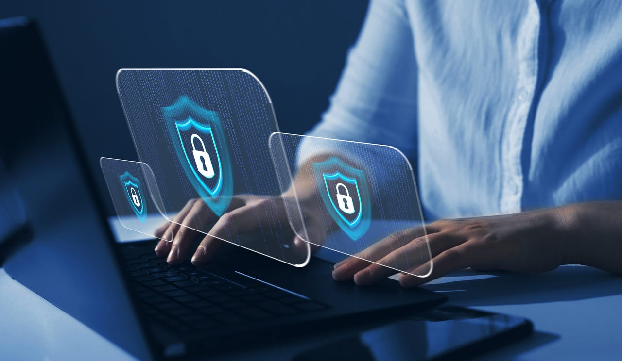 Hands typing on laptop with security locks above it